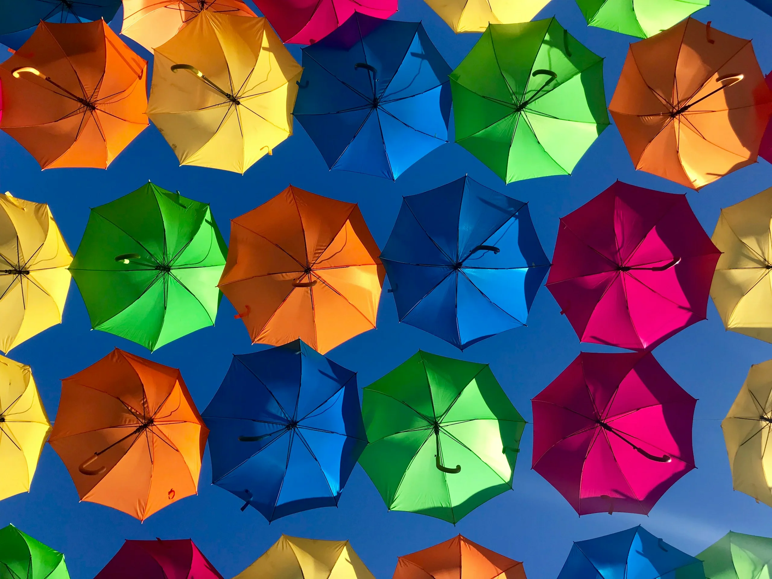Paraguas de colores suspendidos sobre un cielo azul.